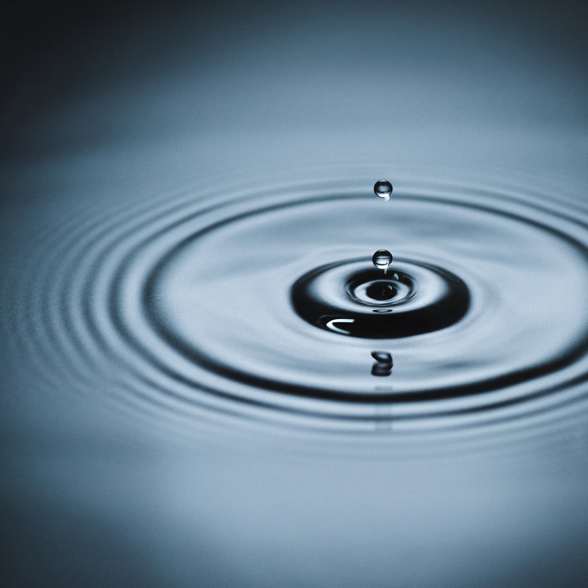 Droplet of purified water falling into glass dish symbolizing pharmaceutical pure media generation for PW and WFI utilities