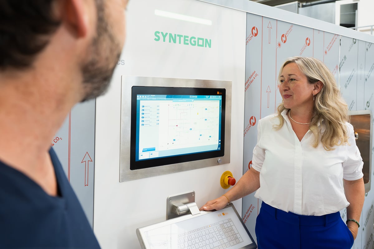 Syntegon experts discussing sterilization process parameters at the control panel of a pharmaceutical production system.