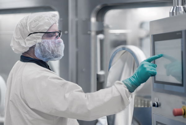 Bediener verwendet integrierte Isolatortechnologie zur aseptischen RTU-Abfüllung in einer sterilen pharmazeutischen Produktionsumgebung