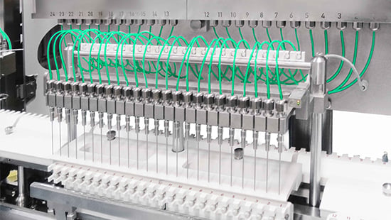 Zeit-Druck-Abfüllsystem mit mehreren Düsen und grüner Schlauchführung integriert in eine pharmazeutische Abfüllmaschine für schnelle, präzise Dosierung in aseptischen Umgebungen.